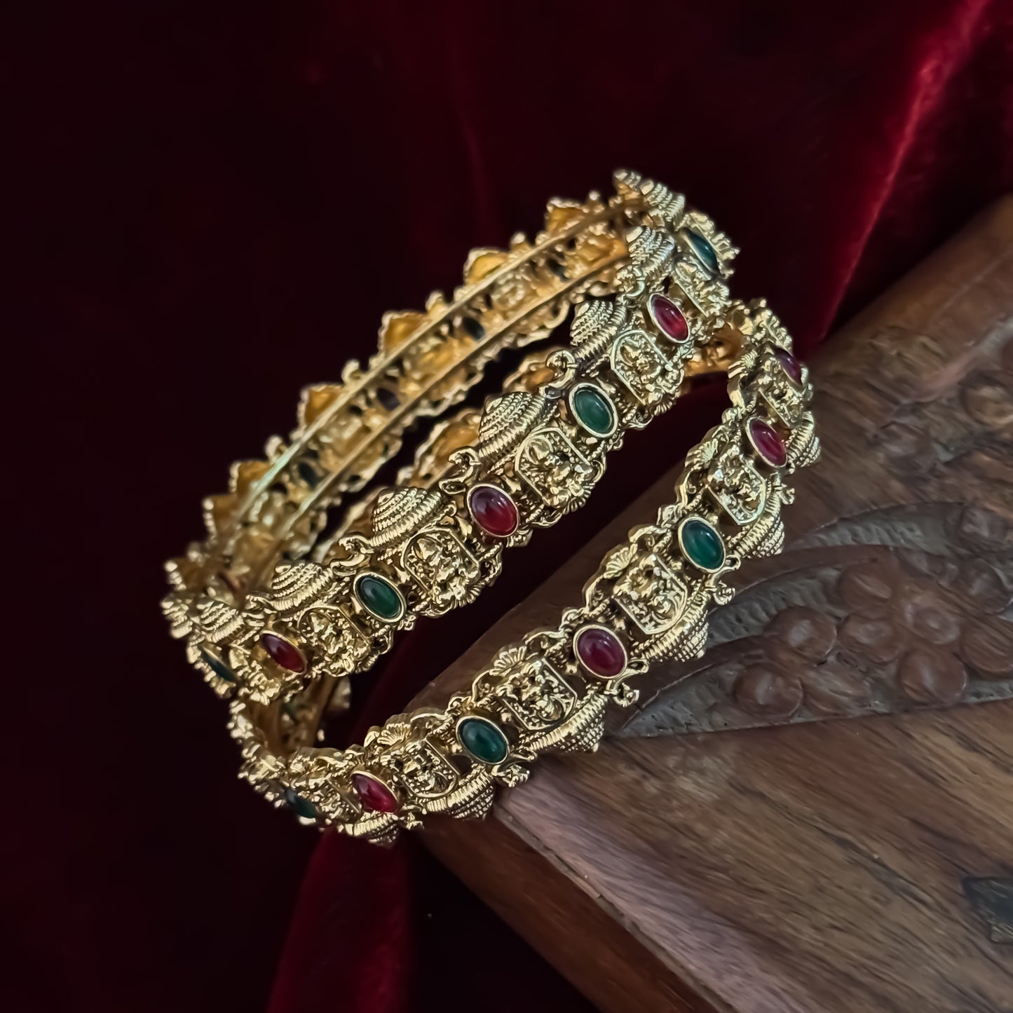 Swarnika premium antique gold temple bangles featuring continuous rows of sculpted goddess lakshmi motifs pink and green stones
