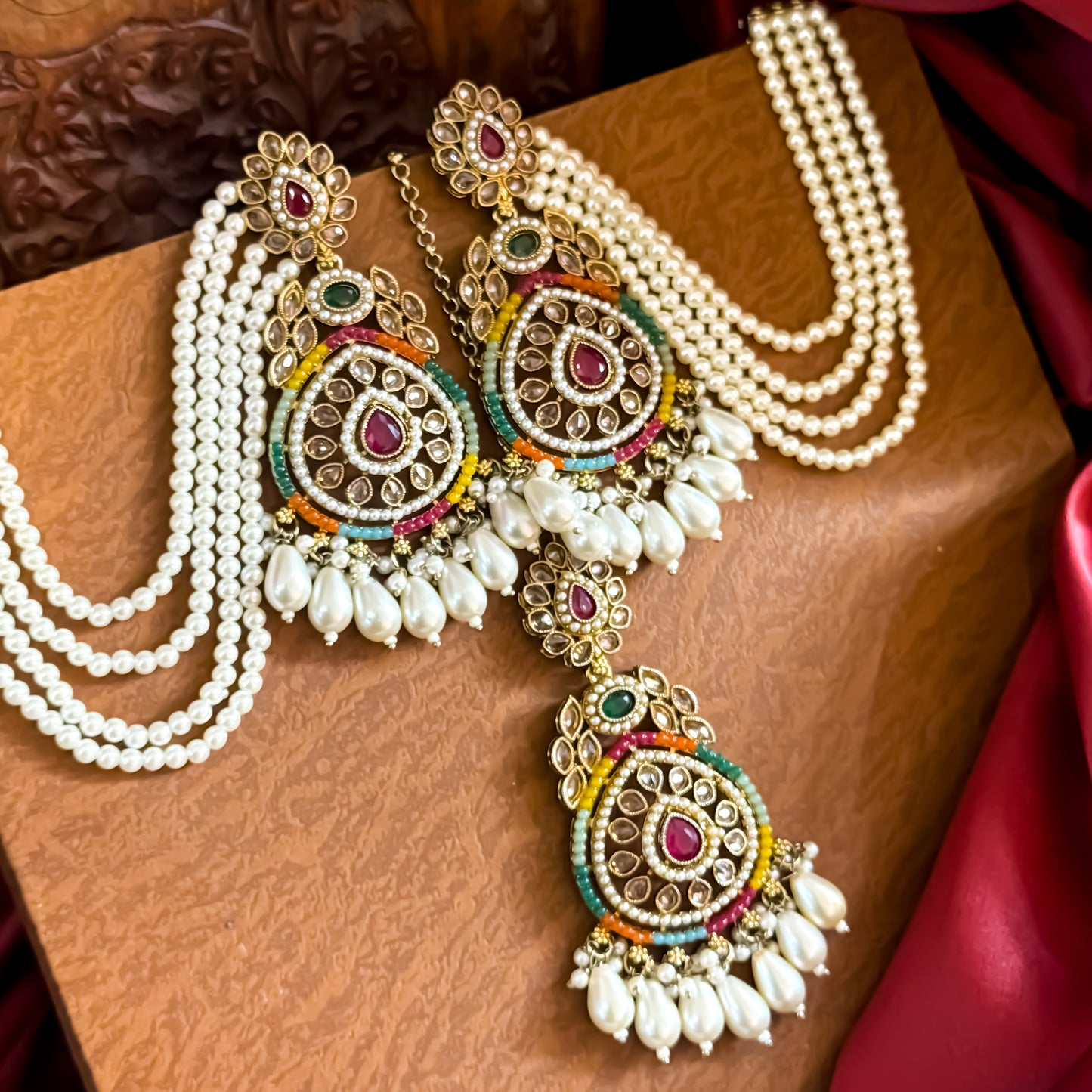 Kanika premium antique gold reverse AD chandbali earrings featuring five layered pearl sahara chains and a matching multicolor maang teeka set flat lay
