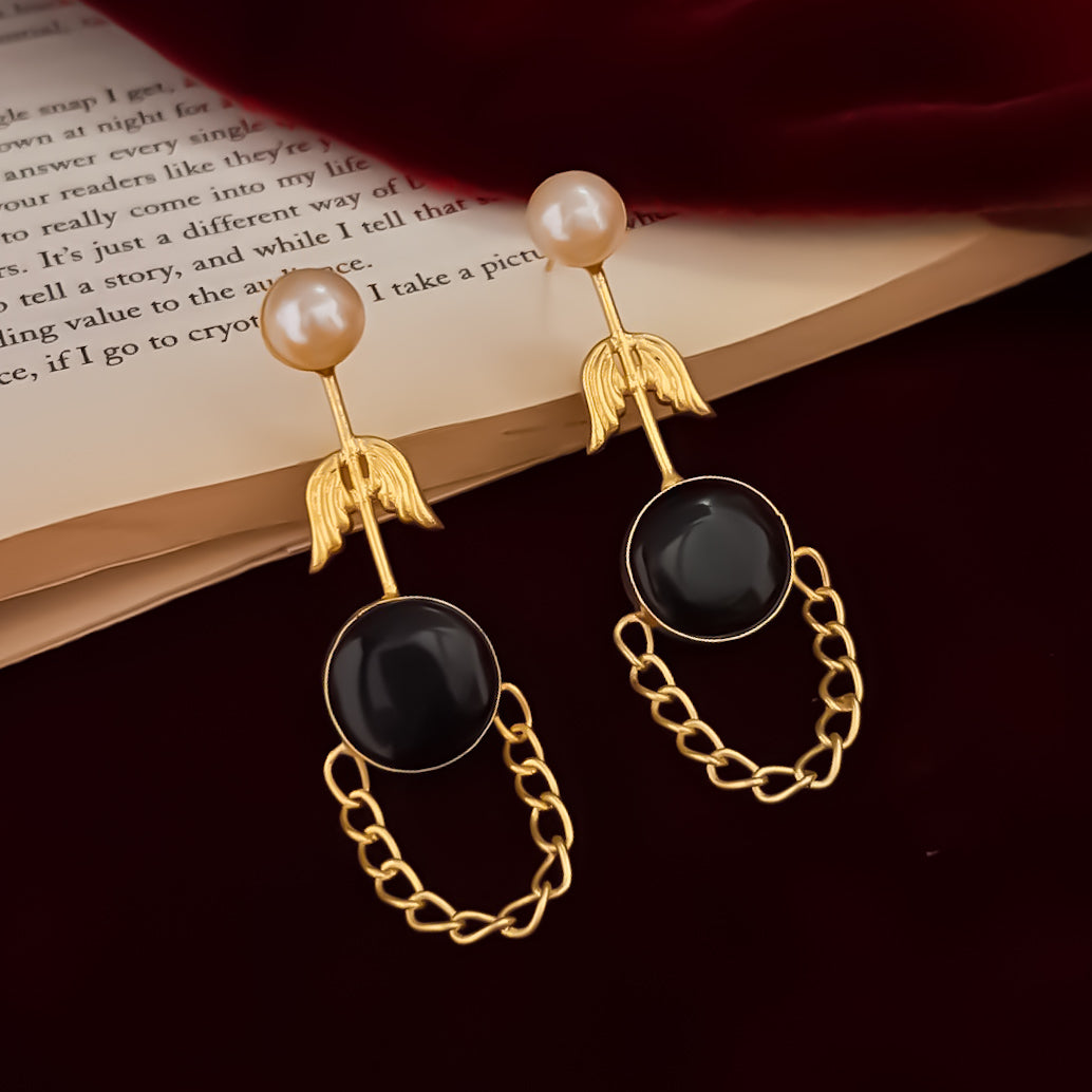 Veena premium brass earrings featuring white pearl studs matte gold leaf stems and round black monalisa stones with looped chain drapes