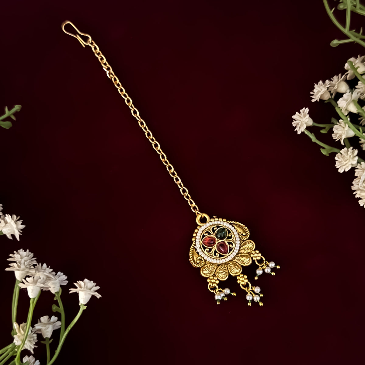 premium antique gold kundan necklace set featuring a multi strand tracking of white pearls and green beads a large central circular medallion with red and green stones and matching rectangular tiered drop earrings