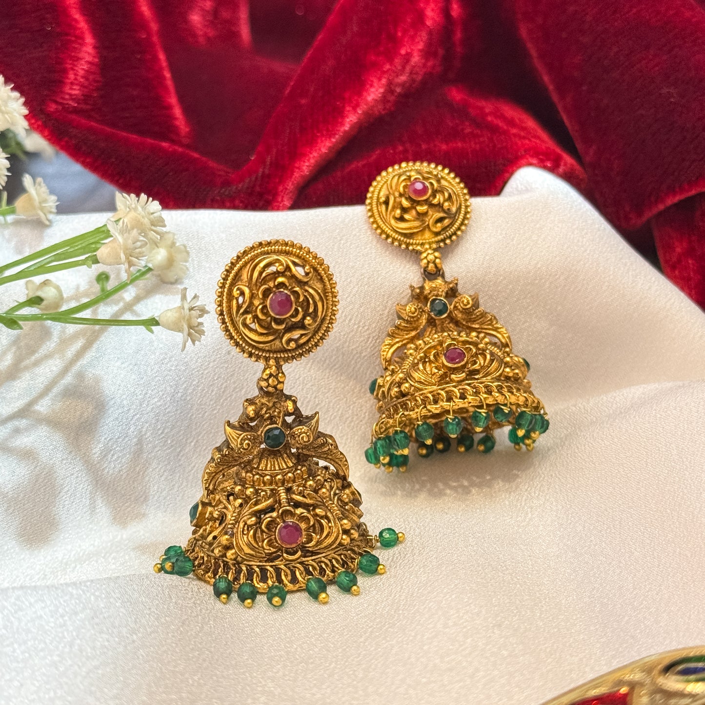 Gauri Kemp Stone premium antique gold temple earrings featuring circular chakra flower studs twin peacock links with a central green stone and a wide dome jhumka cup with a dense emerald green bead fringe