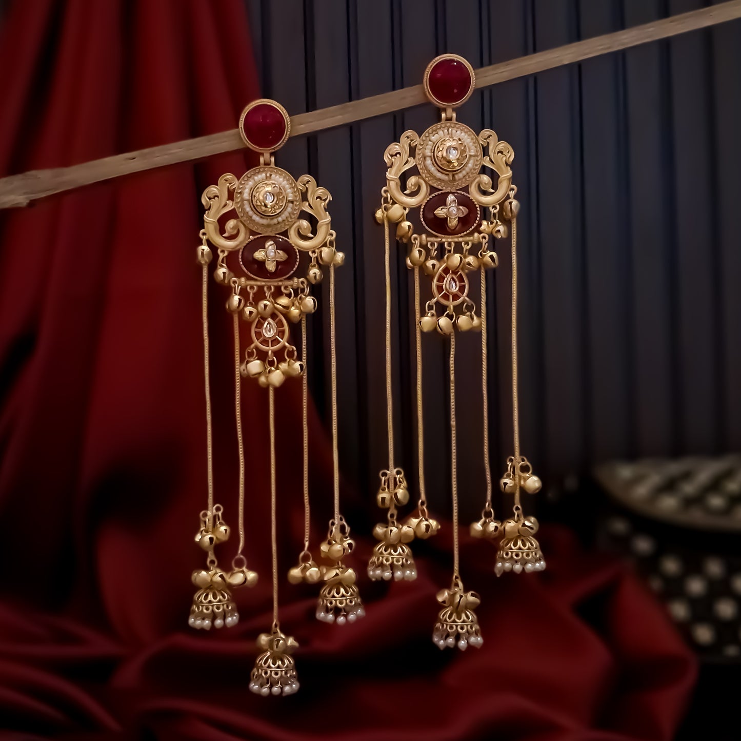 haya premium matte gold kashmiri earrings featuring round ruby studs openwork peacock filigree shields quatrefoil maroon enamel medallions and five long dangling gold chains ending in micro pearl jhumkas