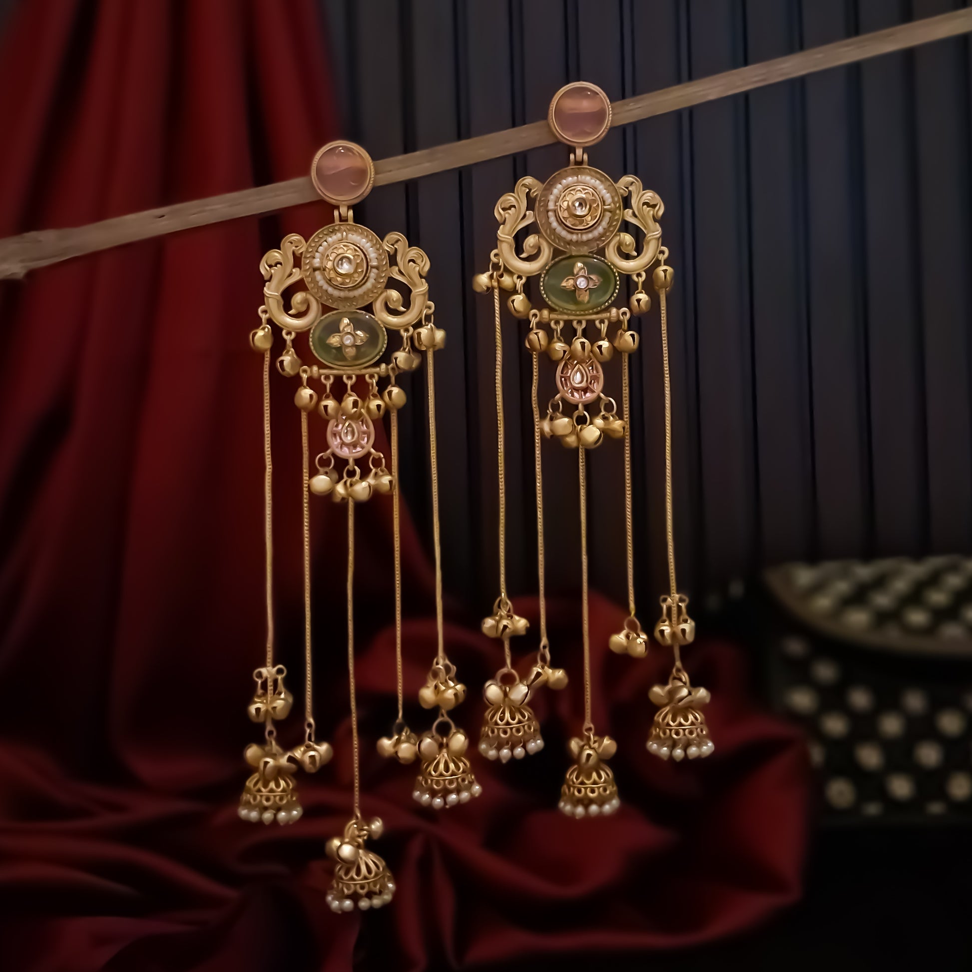 Chaya premium matte gold kashmiri earrings featuring round ruby studs openwork peacock filigree shields quatrefoil maroon enamel medallions and five long dangling gold chains ending in micro pearl jhumkas