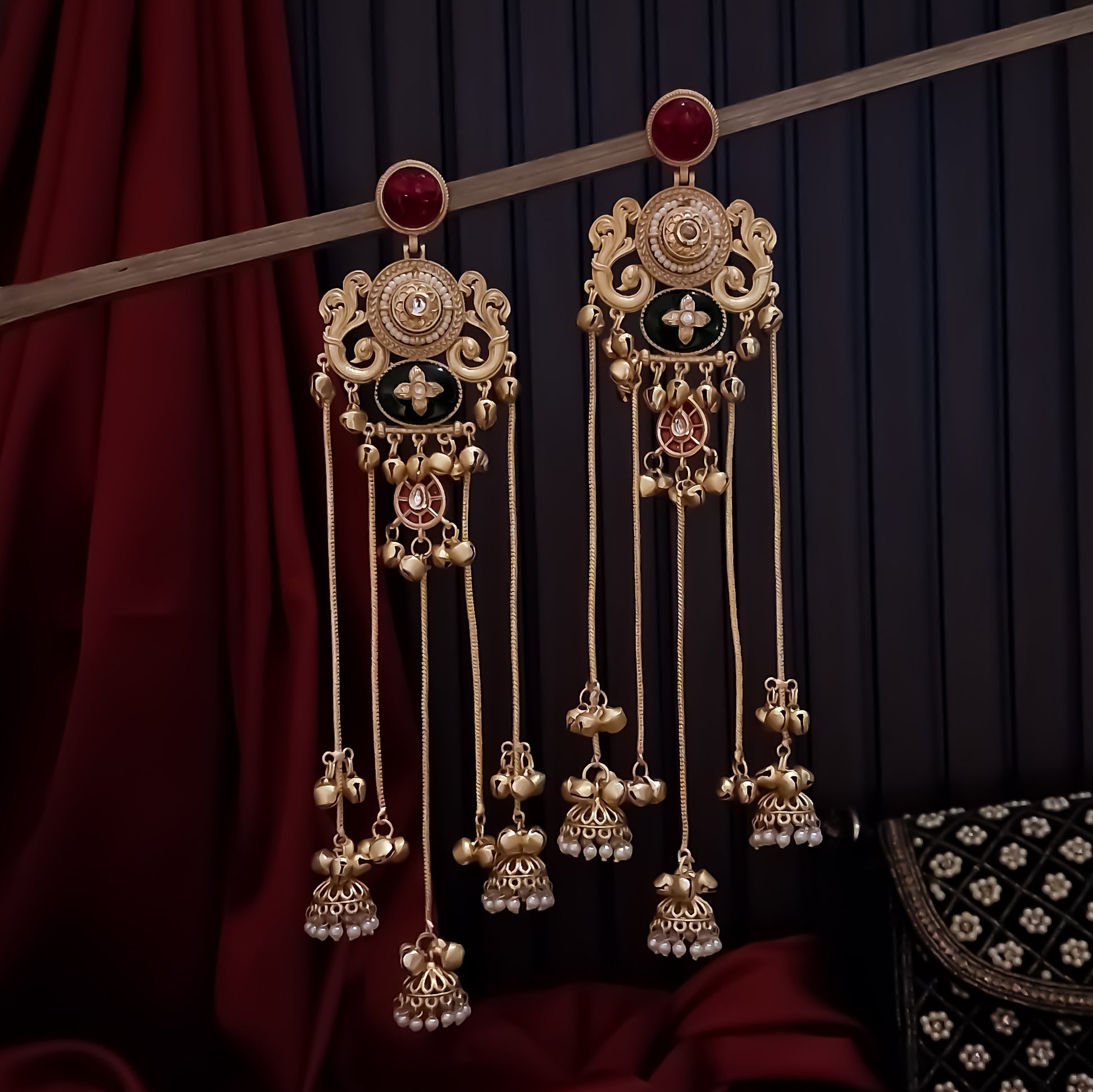Chaya premium matte gold kashmiri earrings featuring round ruby studs openwork peacock filigree shields quatrefoil maroon enamel medallions and five long dangling gold chains ending in micro pearl jhumkas