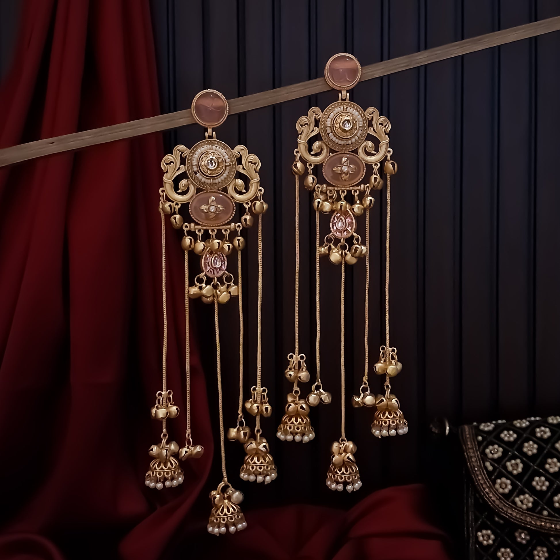 Chaya premium matte gold kashmiri earrings featuring round ruby studs openwork peacock filigree shields quatrefoil maroon enamel medallions and five long dangling gold chains ending in micro pearl jhumkas