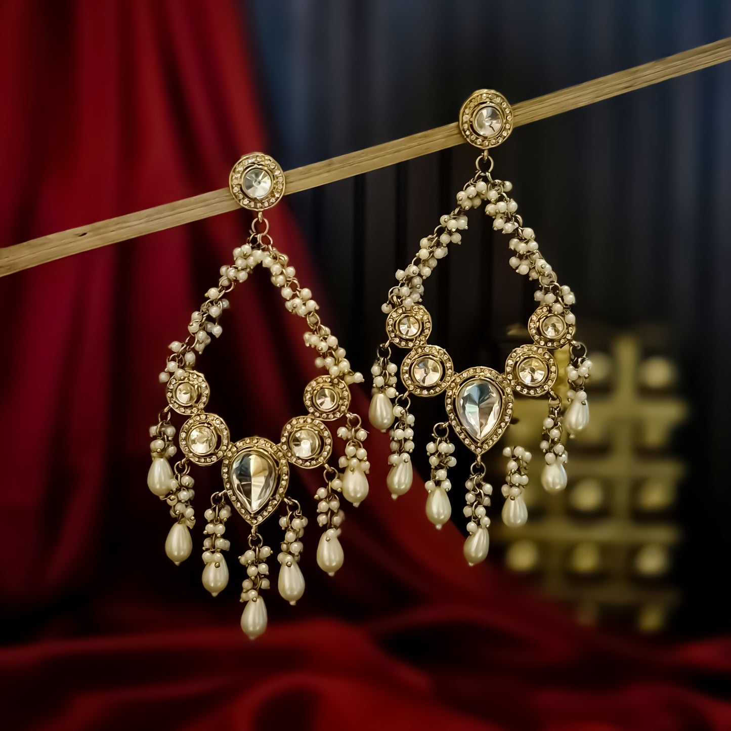 Traditional Indian large teardrop kundan bridal chandelier earrings with ivory pearl fringes next to a close up jewelry product shot