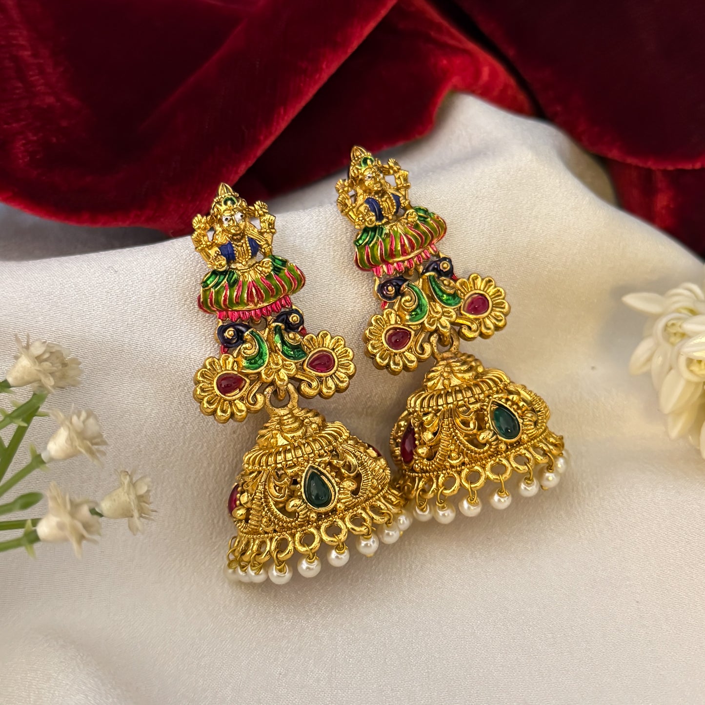 Gaurika premium antique gold temple earrings featuring goddess lakshmi studs twin peacock links with red and green meenakari enamel and an engraved dome jhumka cup with a dense white seed pearl fringe