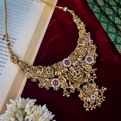 Avani Temple premium antique gold choker necklace featuring a broad central stacked pendant encrusted with pink and green kemp stones twin peacocks a gold ghungroo fringe and matching dome jhumka earrings