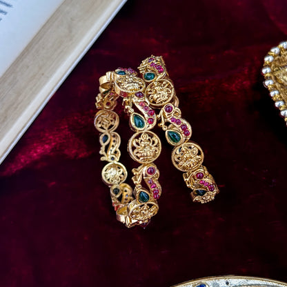 premium antique gold temple bangles featuring continuous rows of sculpted goddess lakshmi motifs square green stones and maroon halos