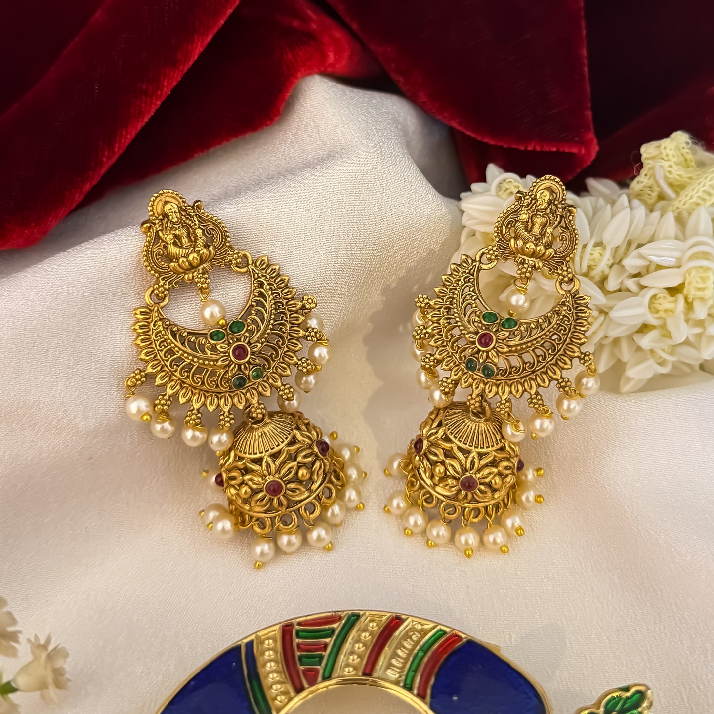 Chandrika Kemp Stone premium antique gold temple earrings featuring leaf shaped goddess lakshmi studs a crescent chandbali medallion frame with red and green stones and an engraved dome jhumka cup with a dense white seed pearl fringe