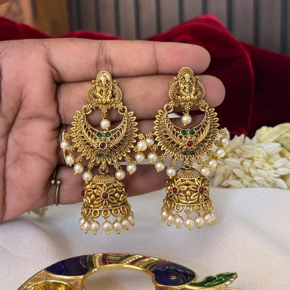 Chandrika Kemp Stone premium antique gold temple earrings featuring leaf shaped goddess lakshmi studs a crescent chandbali medallion frame with red and green stones and an engraved dome jhumka cup with a dense white seed pearl fringe