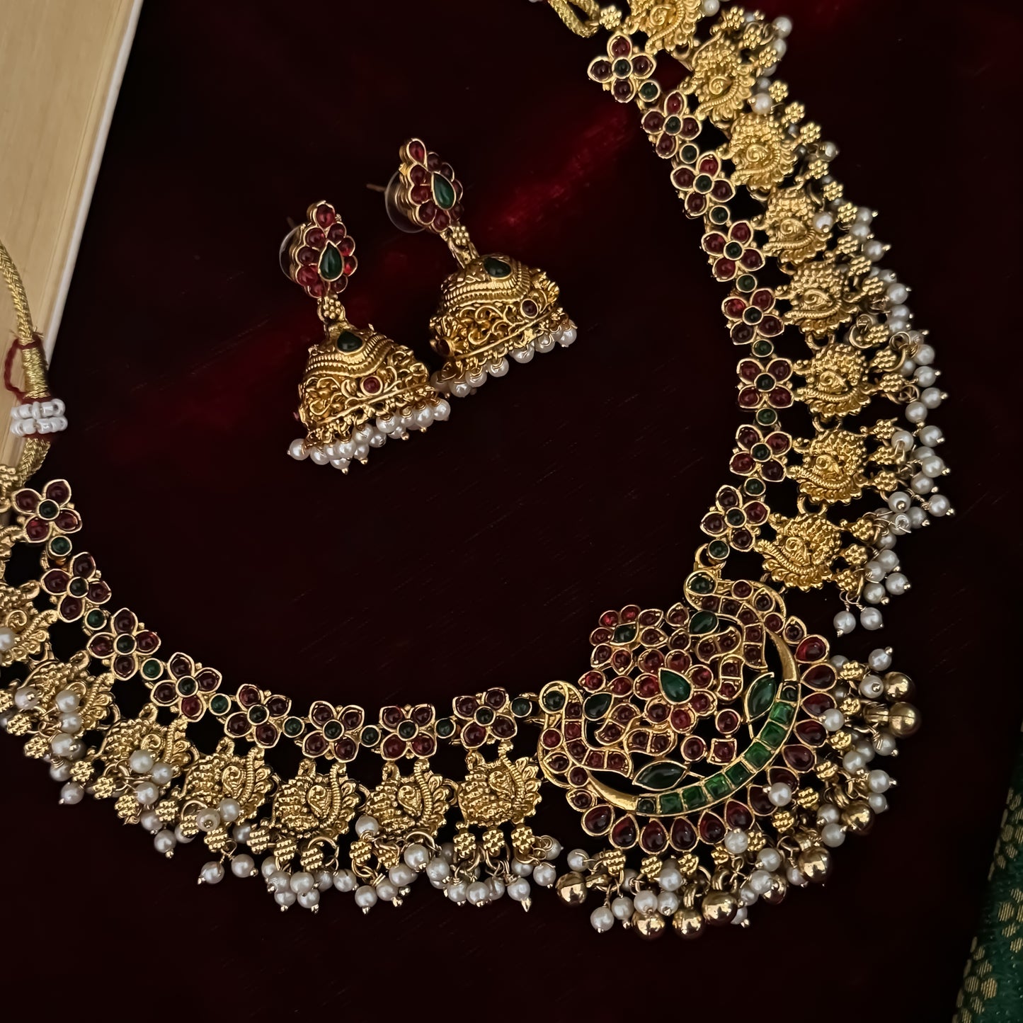 Kalyani premium antique gold temple necklace set featuring continuous rows of floral medallions crescent pendant pink and green stones and pearl drops with matching jhumkas