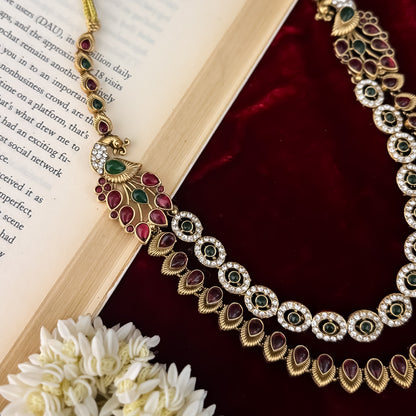 Aarna Temple premium antique gold double layer choker necklace featuring two linked tracks of concentric round green stones and a cascading bottom fringe of ruby red teardrop stones alongside matching chandelier earrings