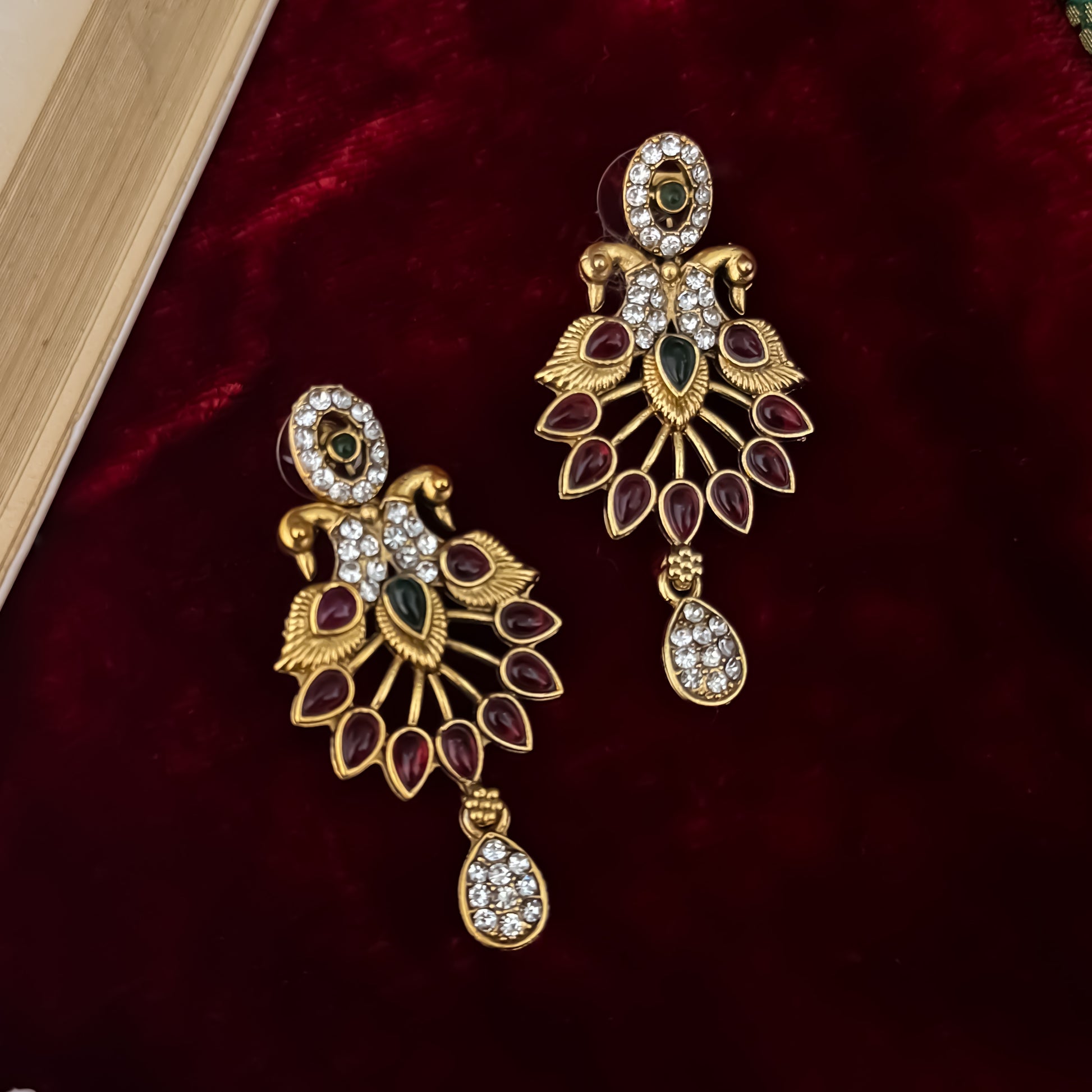 Aarna Temple premium antique gold double layer choker necklace featuring two linked tracks of concentric round green stones and a cascading bottom fringe of ruby red teardrop stones alongside matching chandelier earrings