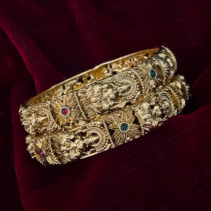 premium antique gold temple bangles featuring continuous rows of sculpted goddess lakshmi motifs square green stones and maroon halos