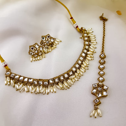 Yashvi premium antique gold kundan sleek collar necklace set featuring a linear linked tracking of clear dabi stones and a dense cascading fringe of white rice pearls with matching hexagonal stud earrings and maang tikka