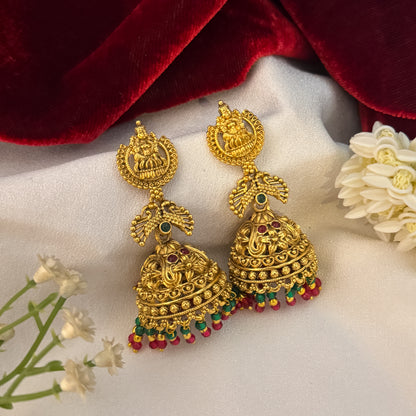 Vatsala Kemp Stone premium antique gold temple earrings featuring goddess lakshmi studs twin peacock links with red and green stones and an engraved dome jhumka cup with a dense white seed pearl fringe