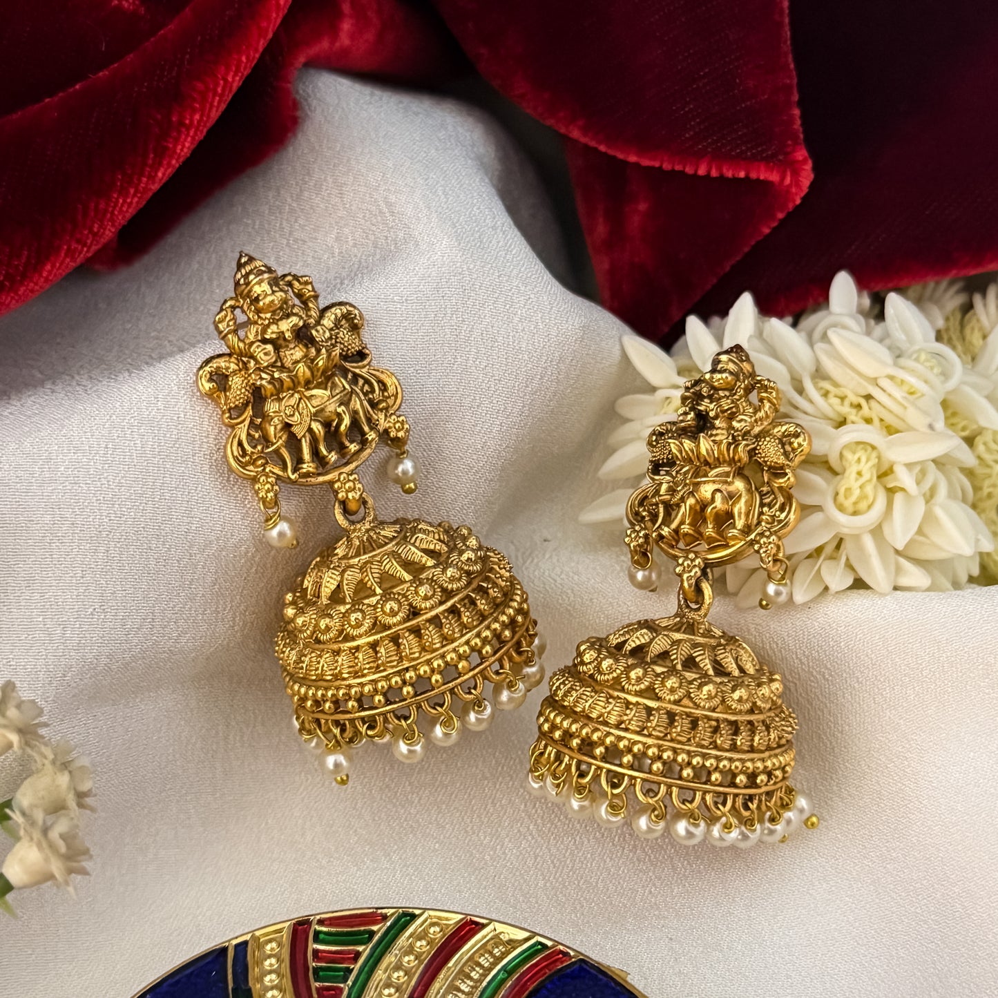 Temple Motif Jhumka Earrings featuring premium antique gold Goddess Lakshmi and peacock top studs holding a wide flared dome cup with a dense cascading white seed pearl fringe