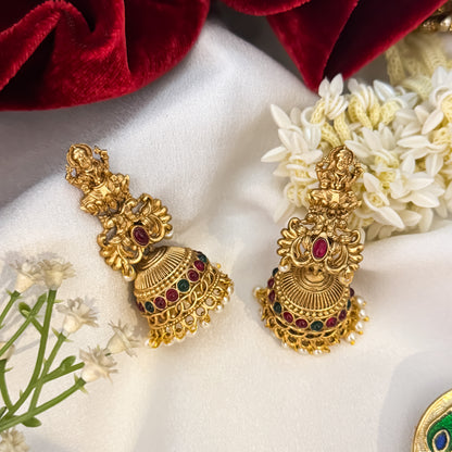Siddhi Kemp Stone premium antique gold temple earrings featuring goddess lakshmi studs twin peacock links with a central red stone and a wide dome jhumka cup rimmed with multi color stones and a dense white seed pearl fringe