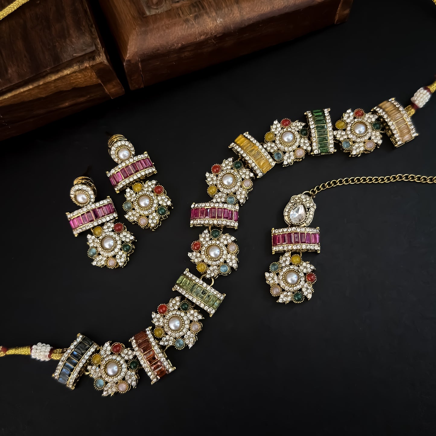 Ashwini Sabyasachi style premium antique gold kundan multi color necklace set featuring a segmented panel collar tracking of multi shape multicolored gemstone baguettes sunburst kundan rosettes white pearls matching tiered earrings and maang tikka