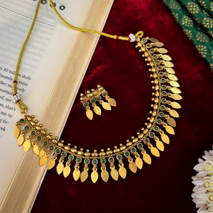 Kaira Temple premium antique gold choker necklace featuring a linear track of round emerald green kemp stones a top row of gold beads a bottom cascading fringe of flat coin leaf drops and matching earrings