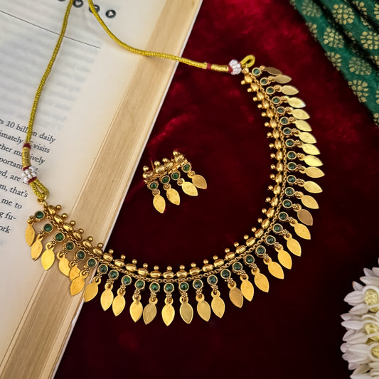 Kaira Temple premium antique gold choker necklace featuring a linear track of round emerald green kemp stones a top row of gold beads a bottom cascading fringe of flat coin leaf drops and matching earrings
