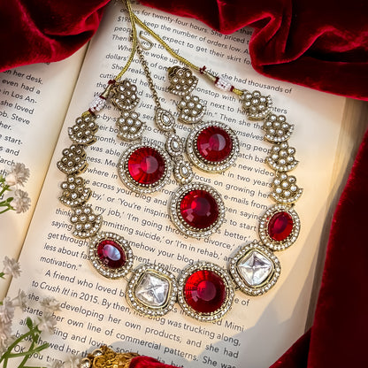 Naira AD premium gold plated necklace set featuring a linear linked tracking of clear mock polki crystal halos a central circular deep wine plum stone medallion matching tiered earrings and a maang tikka