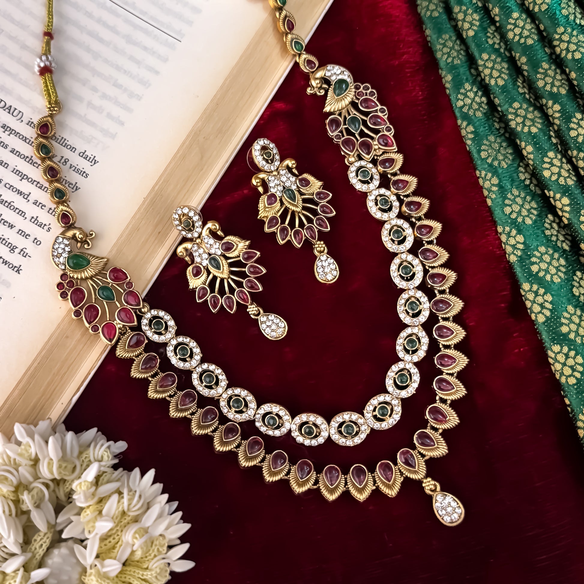 Aarna Temple premium antique gold double layer choker necklace featuring two linked tracks of concentric round green stones and a cascading bottom fringe of ruby red teardrop stones alongside matching chandelier earrings