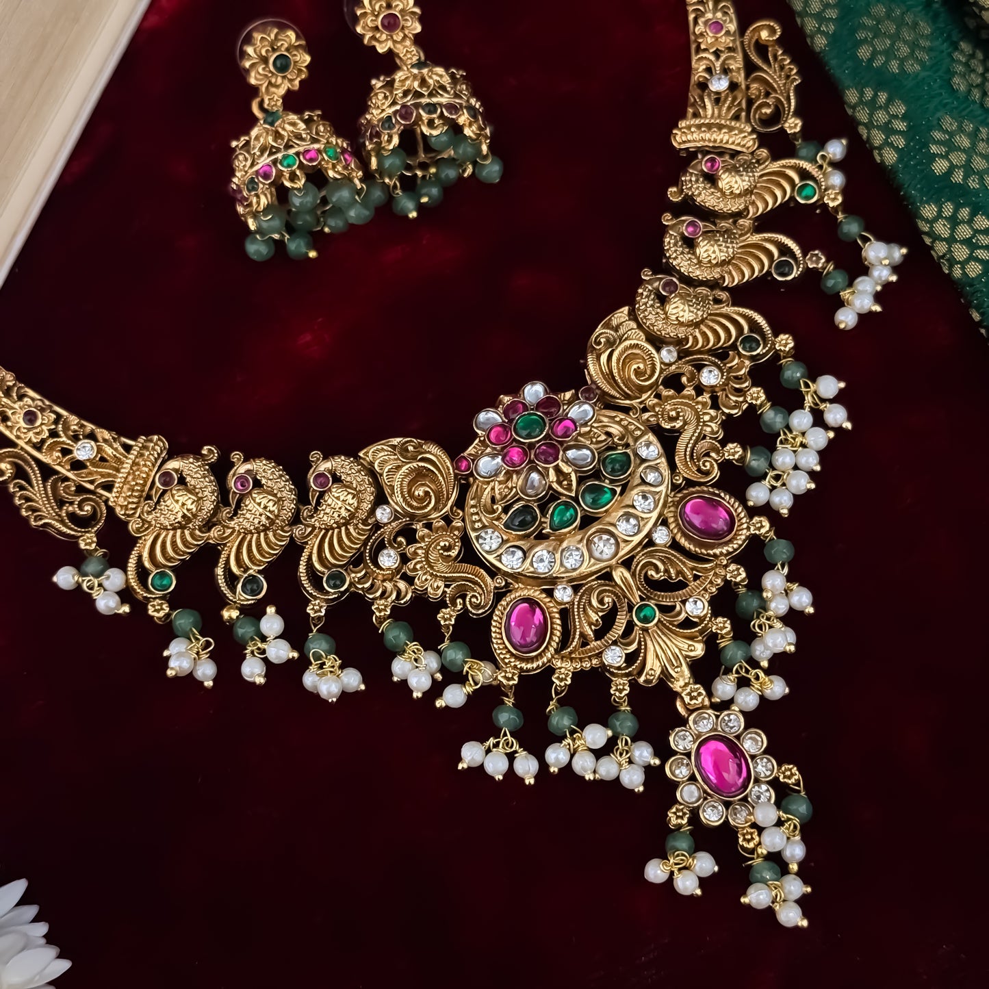 Hansani Temple premium antique gold long necklace set featuring a linked peacock chain a crescent chandbali pendant with red and green stones a dense bead fringe and matching dome jhumka earrings