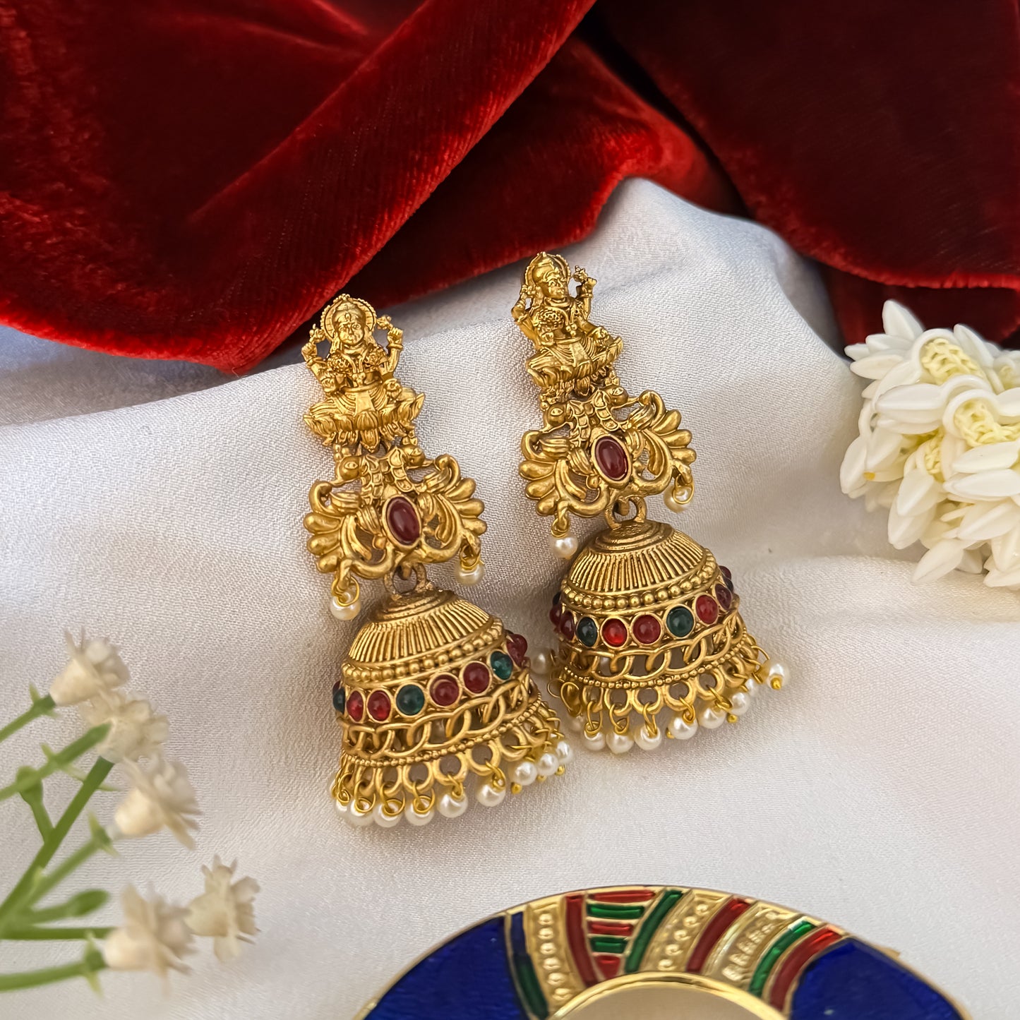 Siddhi Kemp Stone premium antique gold temple earrings featuring goddess lakshmi studs twin peacock links with a central red stone and a wide dome jhumka cup rimmed with multi color stones and a dense white seed pearl fringe