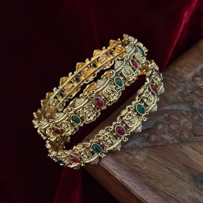 Swarnika premium antique gold temple bangles featuring continuous rows of sculpted goddess lakshmi motifs pink and green stones
