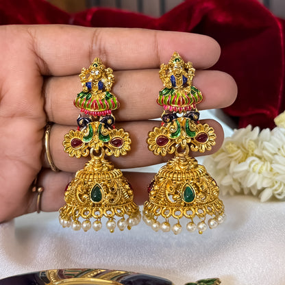 Gaurika premium antique gold temple earrings featuring goddess lakshmi studs twin peacock links with red and green meenakari enamel and an engraved dome jhumka cup with a dense white seed pearl fringe