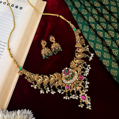 Hansani Temple premium antique gold long necklace set featuring a linked peacock chain a crescent chandbali pendant with red and green stones a dense bead fringe and matching dome jhumka earrings