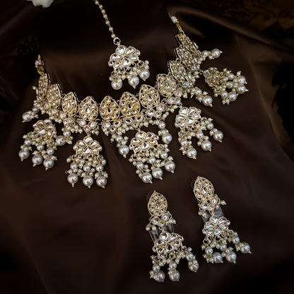 premium antique gold kundan broad choker necklace set featuring a linear linked tracking of crescent chandbali medallions dense white cluster pearl fringes matching chandelier earrings and maang tikka