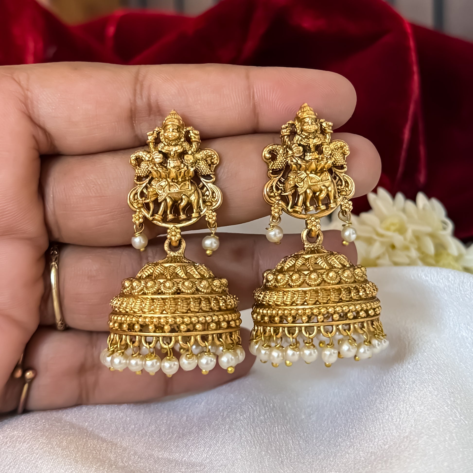Temple Motif Jhumka Earrings featuring premium antique gold Goddess Lakshmi and peacock top studs holding a wide flared dome cup with a dense cascading white seed pearl fringe