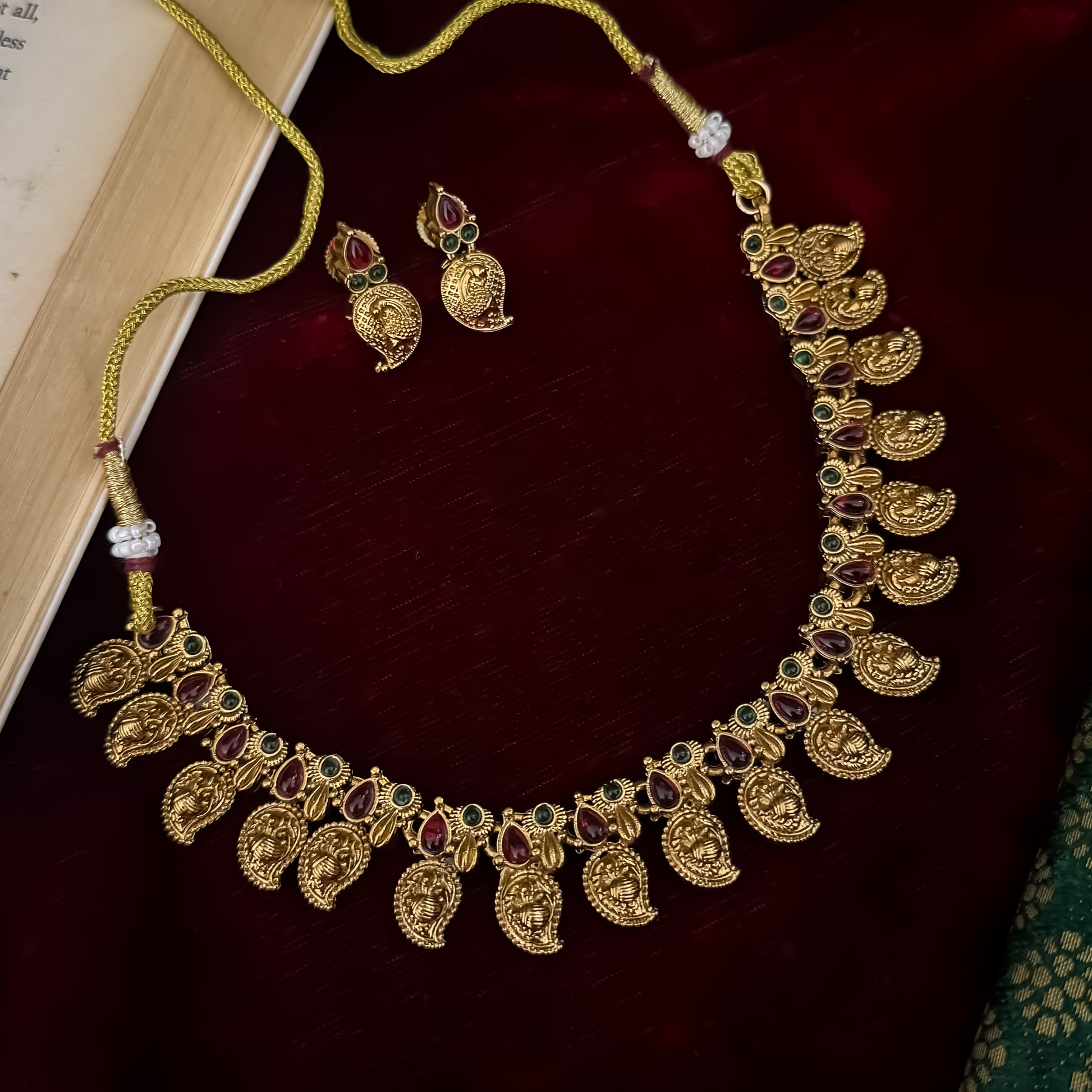 Amrapali leaf Temple gold temple choker necklace set featuring a continuous linked row of paisley manga medallions with alternating pink and green kemp stones alongside matching paisley drop earrings