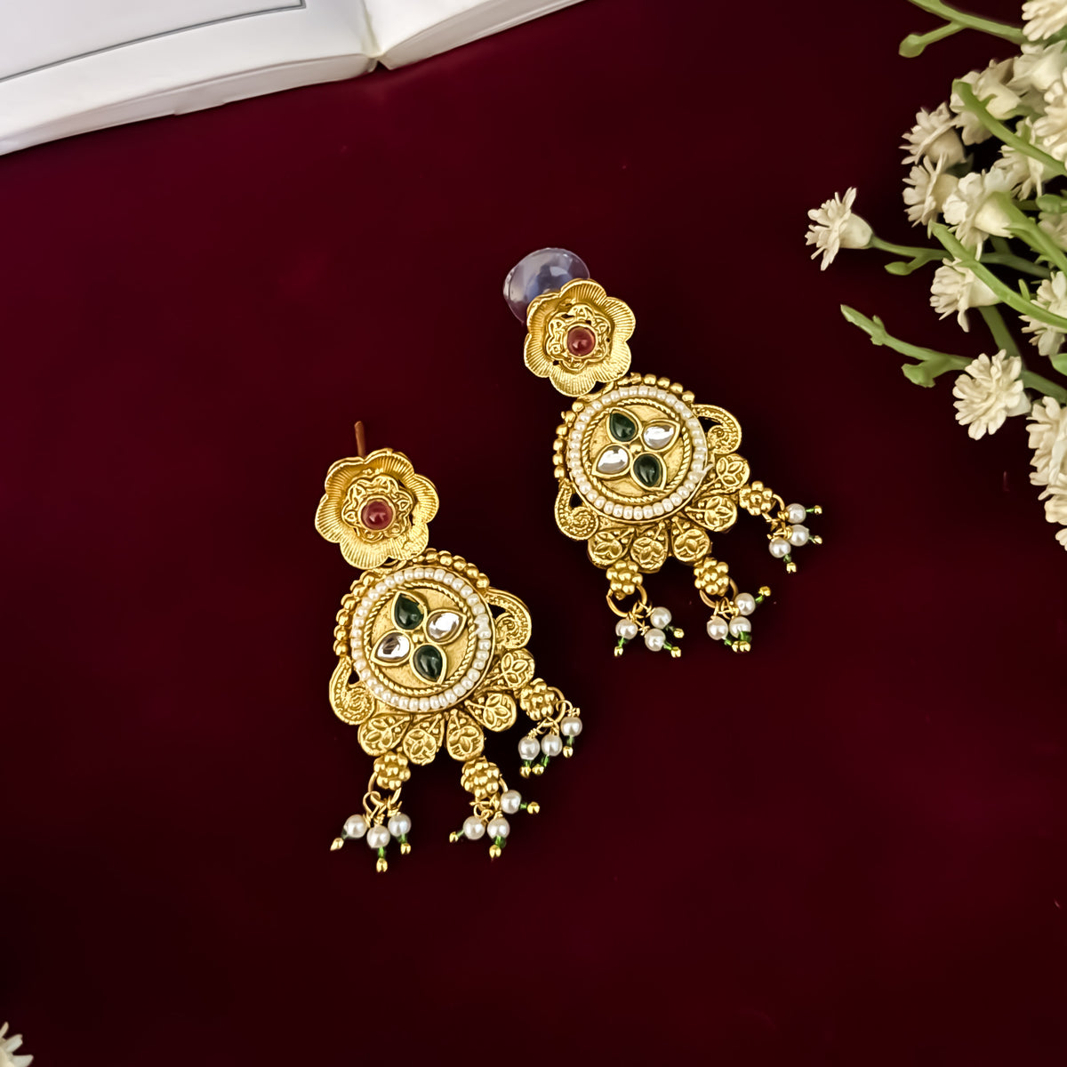 premium antique gold kundan necklace set featuring a multi strand tracking of white pearls and green beads a large central circular medallion with red and green stones and matching rectangular tiered drop earrings