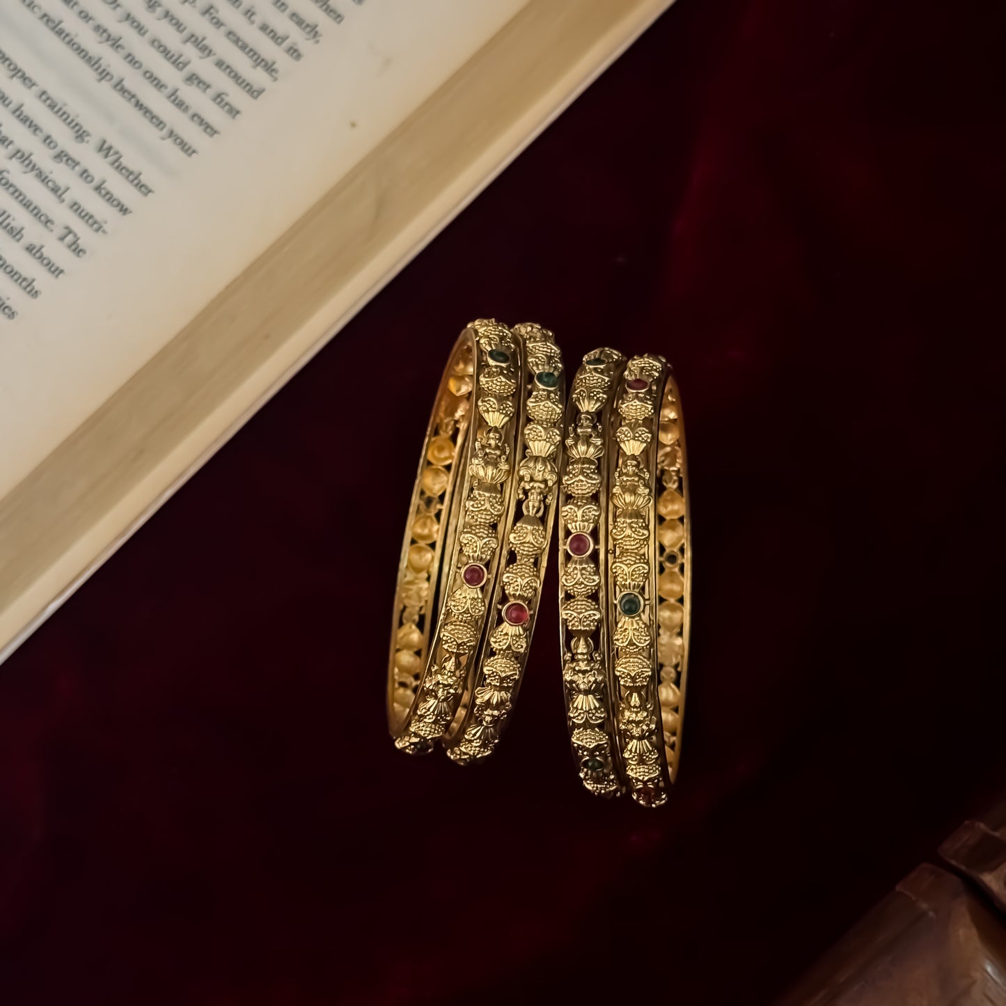 Madhulika premium antique gold temple bangles featuring continuous rows of sculpted goddess lakshmi motifs pink and green stones