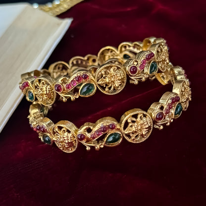 premium antique gold temple bangles featuring continuous rows of sculpted goddess lakshmi motifs square green stones and maroon halos