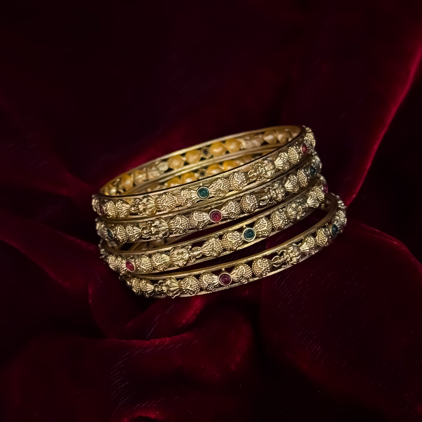 Madhulika premium antique gold temple bangles featuring continuous rows of sculpted goddess lakshmi motifs pink and green stones