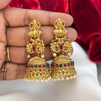 Siddhi Kemp Stone premium antique gold temple earrings featuring goddess lakshmi studs twin peacock links with a central red stone and a wide dome jhumka cup rimmed with multi color stones and a dense white seed pearl fringe