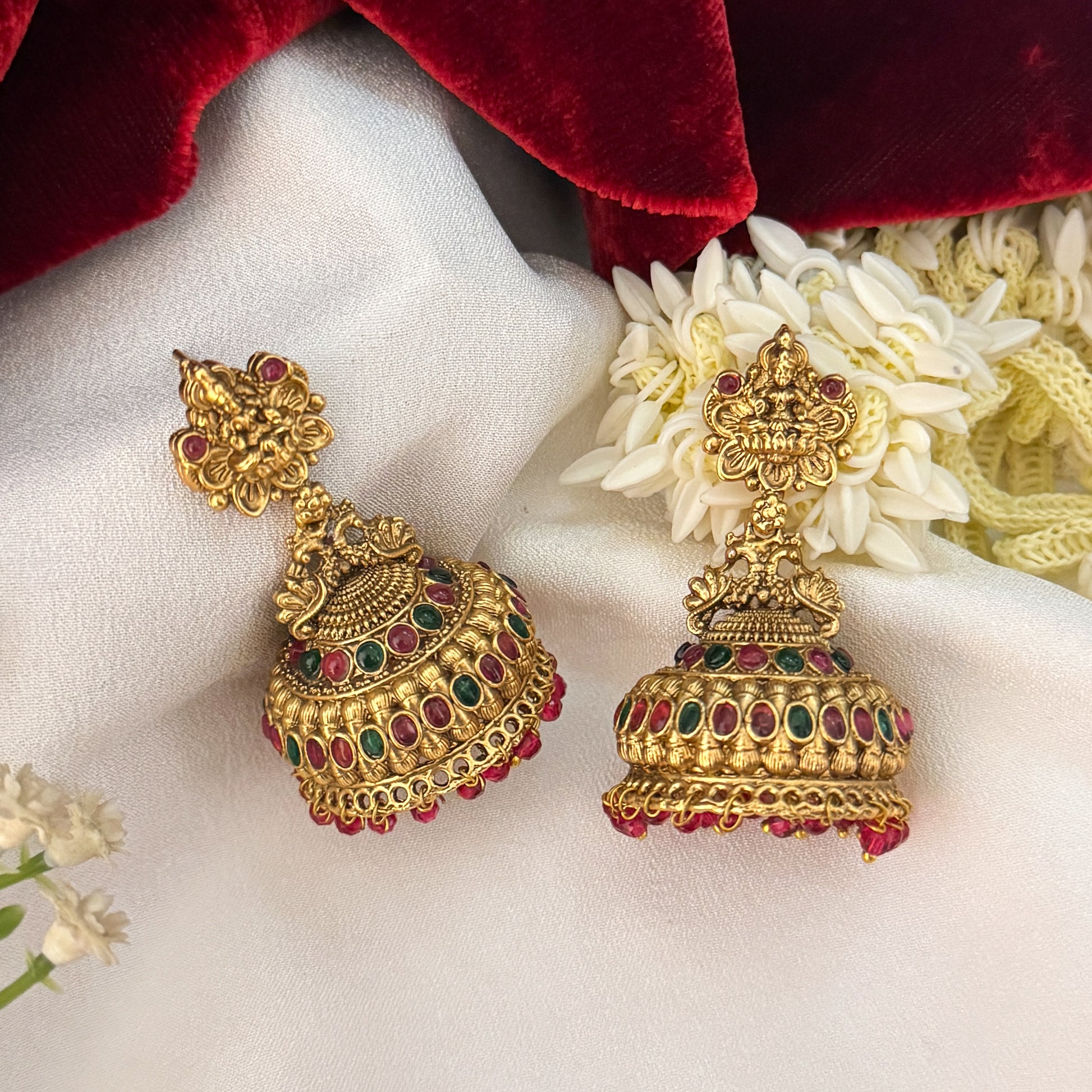 Nishika Temple Motif Jhumka Earrings featuring premium antique gold Goddess Lakshmi and peacock top studs holding a wide flared dome cup with a dense cascading white seed pearl fringe