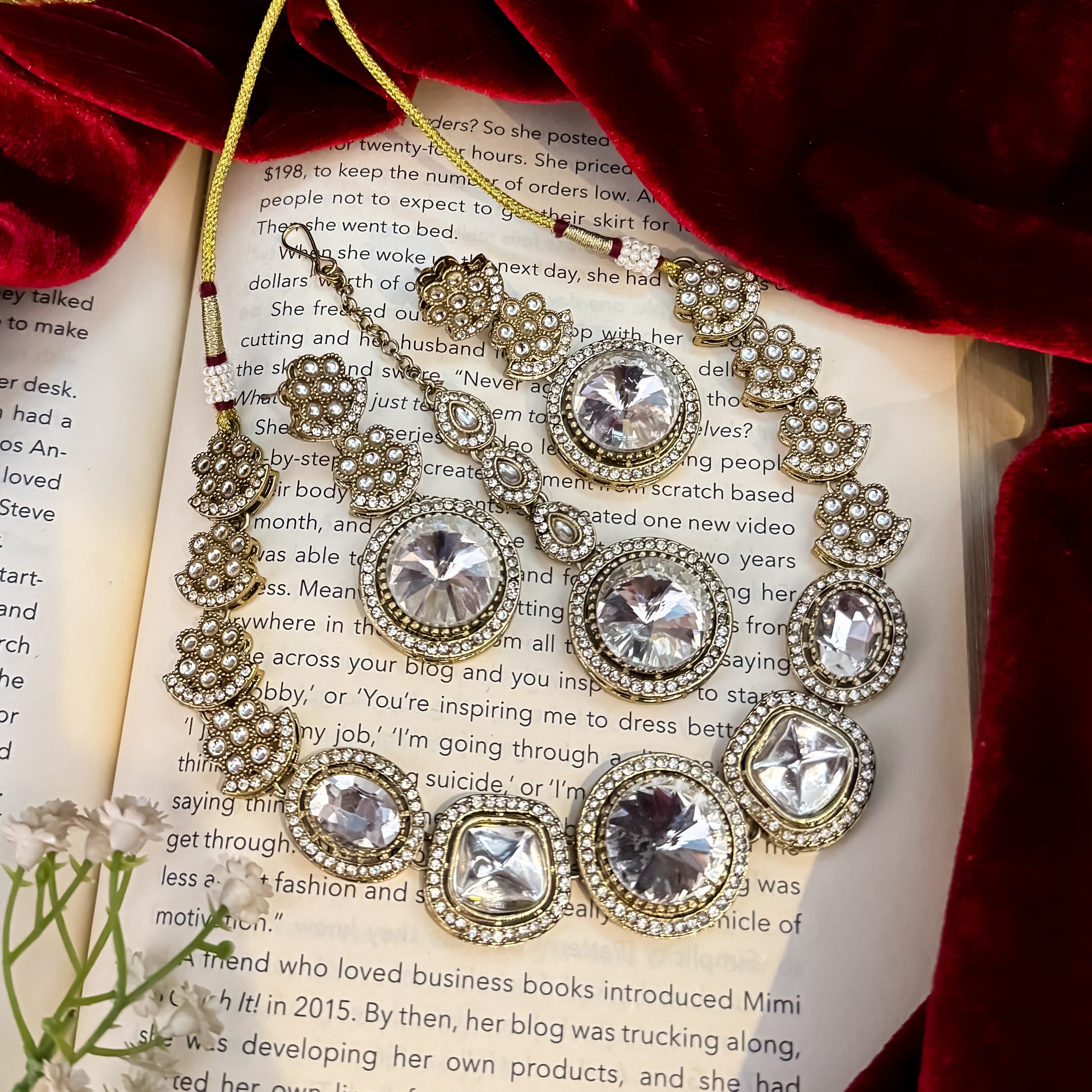 Naira AD premium gold plated necklace set featuring a linear linked tracking of clear mock polki crystal halos a central circular deep wine plum stone medallion matching tiered earrings and a maang tikka