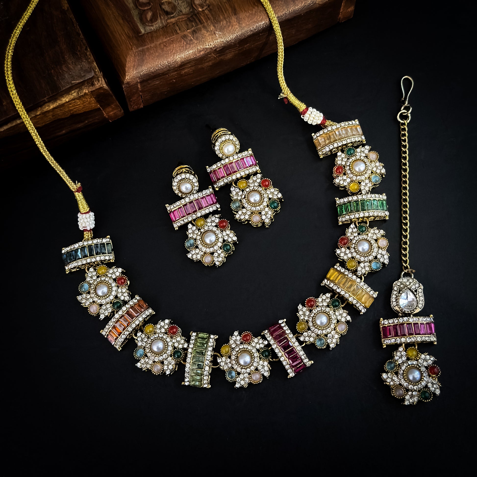 Ashwini Sabyasachi style premium antique gold kundan multi color necklace set featuring a segmented panel collar tracking of multi shape multicolored gemstone baguettes sunburst kundan rosettes white pearls matching tiered earrings and maang tikka