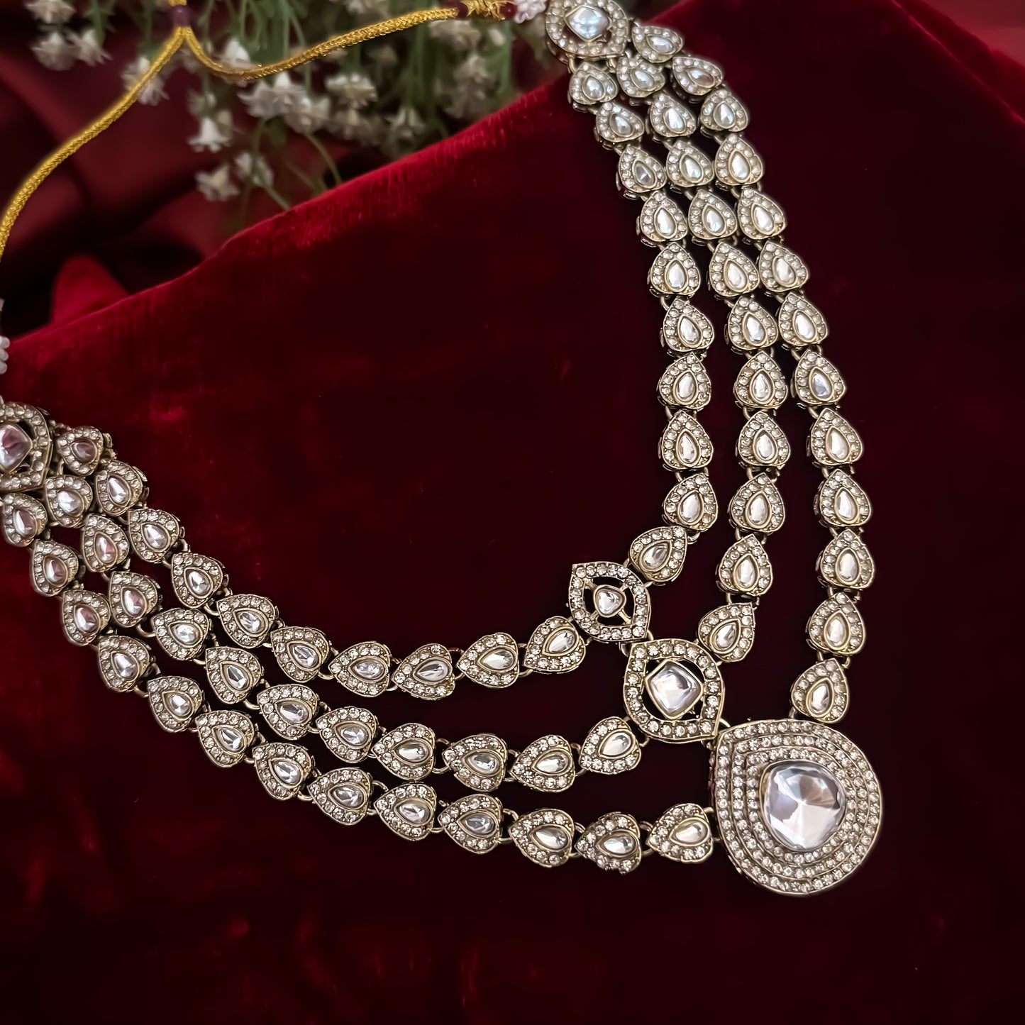 Rashmika premium antique gold kundan triple layer necklace set featuring three parallel cascading tracks of clear dabi mock polki stones a central teardrop pendant line matching drop earrings and maang tikka