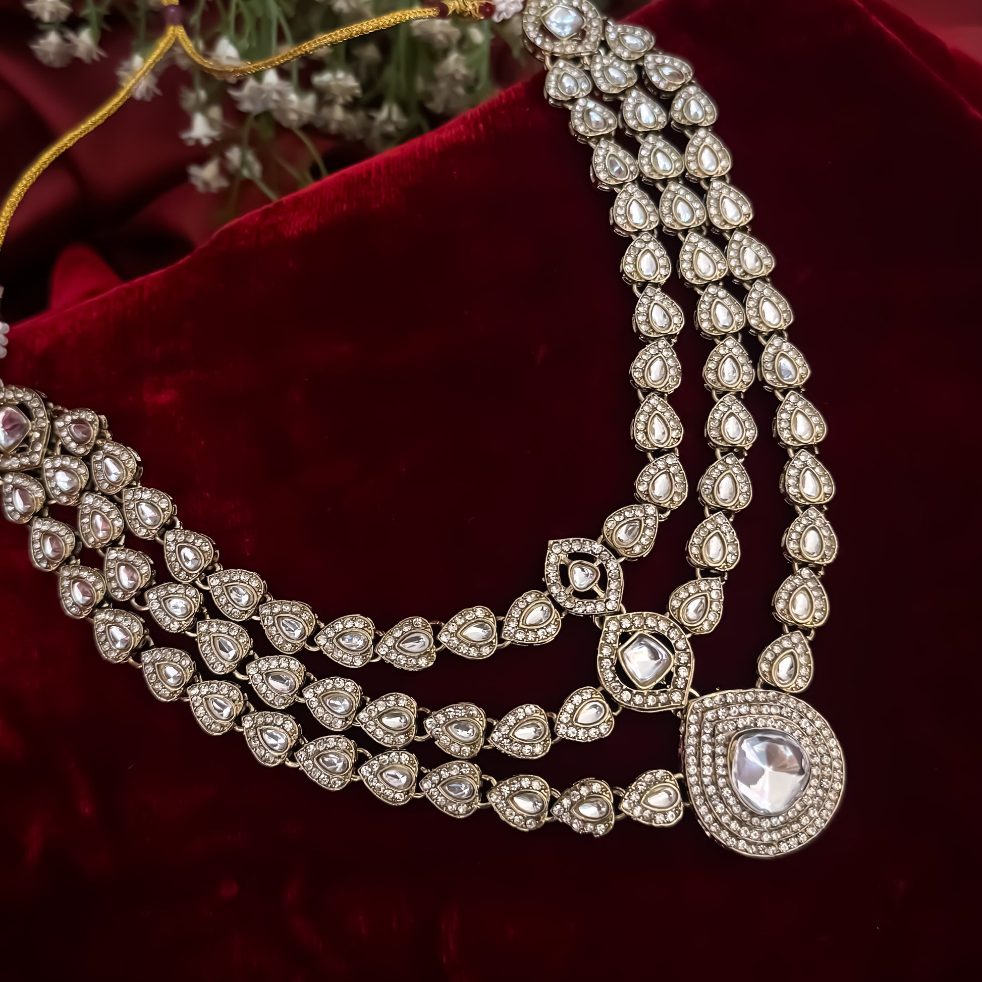 Rashmika premium antique gold kundan triple layer necklace set featuring three parallel cascading tracks of clear dabi mock polki stones a central teardrop pendant line matching drop earrings and maang tikka