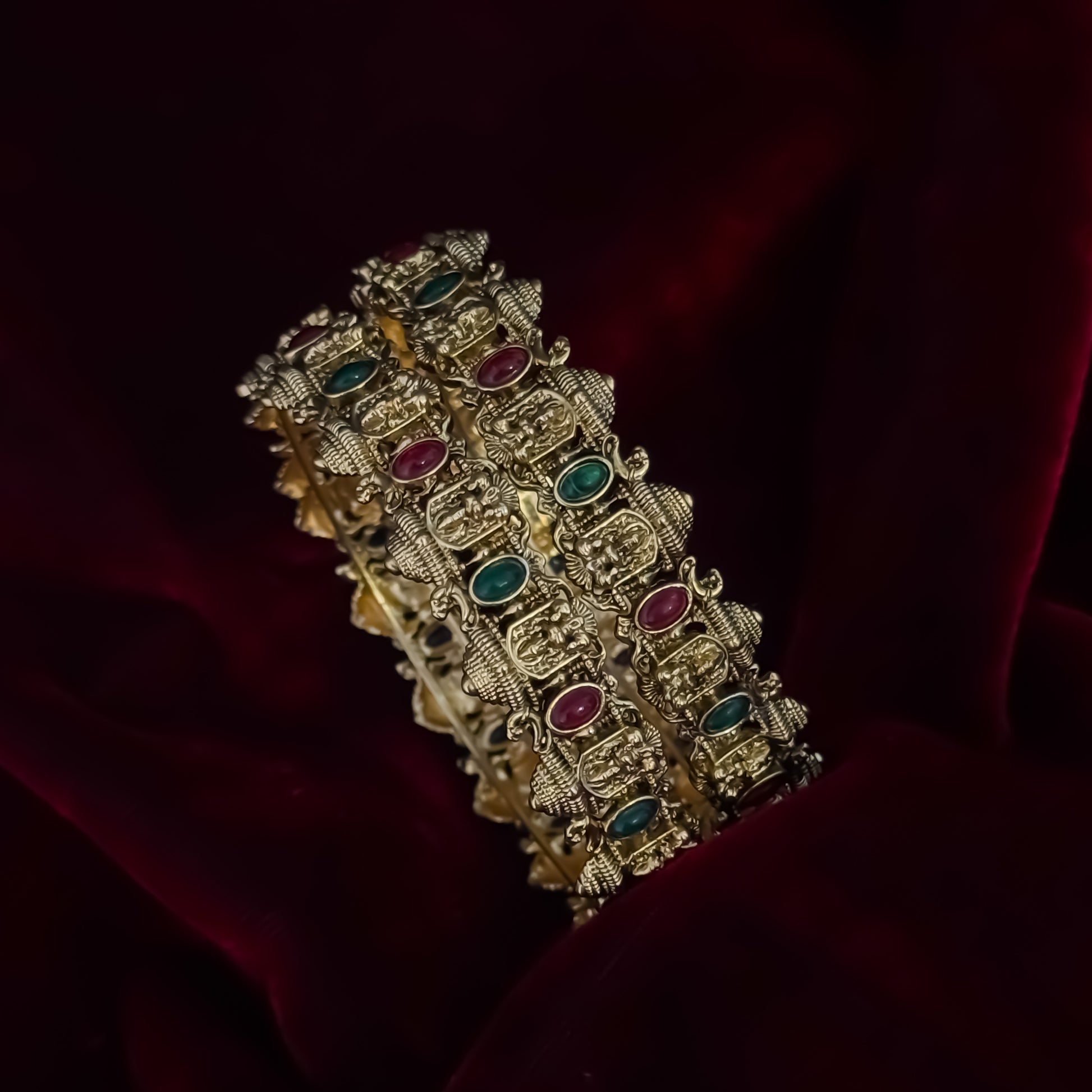 Swarnika premium antique gold temple bangles featuring continuous rows of sculpted goddess lakshmi motifs pink and green stones