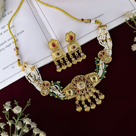 Himangi premium antique gold kundan necklace set featuring a multi strand tracking of white pearls and green beads a large central circular medallion with red and green stones and matching rectangular tiered drop earrings