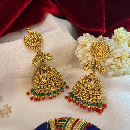 Vatsala Kemp Stone premium antique gold temple earrings featuring goddess lakshmi studs twin peacock links with red and green stones and an engraved dome jhumka cup with a dense white seed pearl fringe