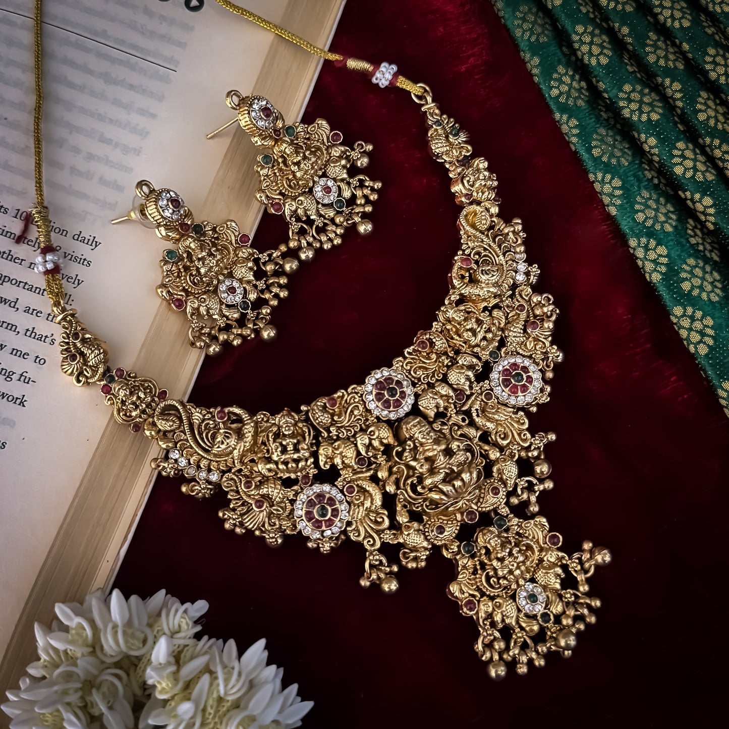 Avani Temple premium antique gold choker necklace featuring a broad central stacked pendant encrusted with pink and green kemp stones twin peacocks a gold ghungroo fringe and matching dome jhumka earrings